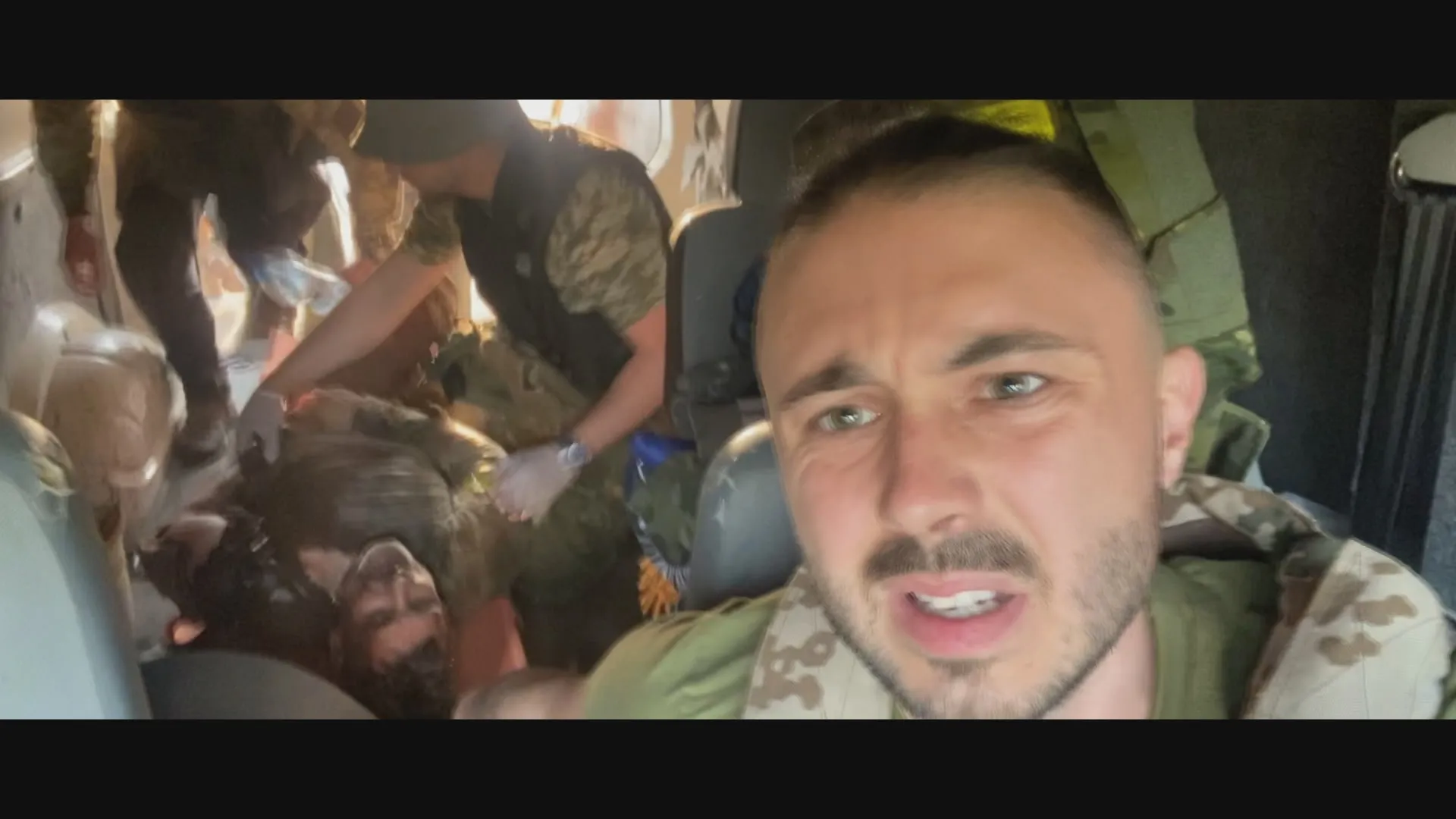 Taras films himself while medics treat wounded soldiers in a military transport