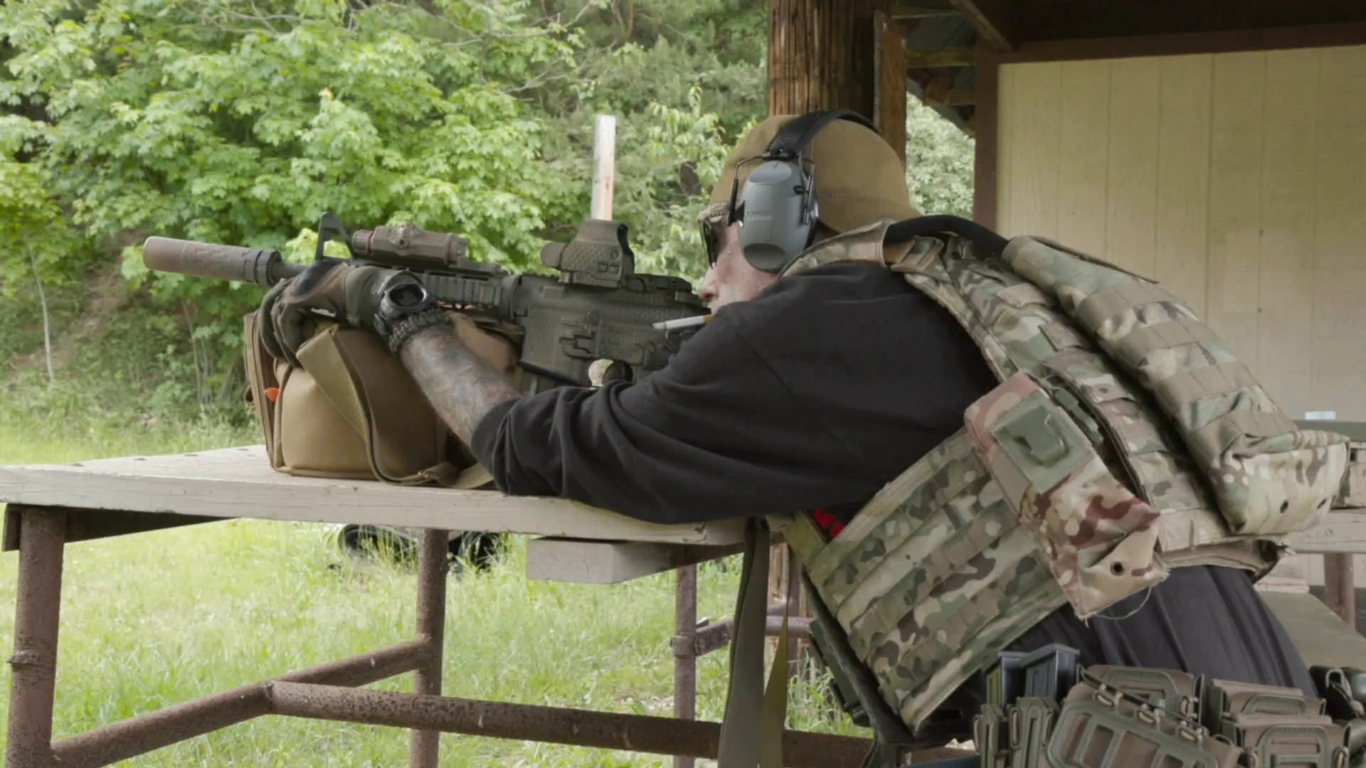 A militia member fires a rifle at an outdoor range